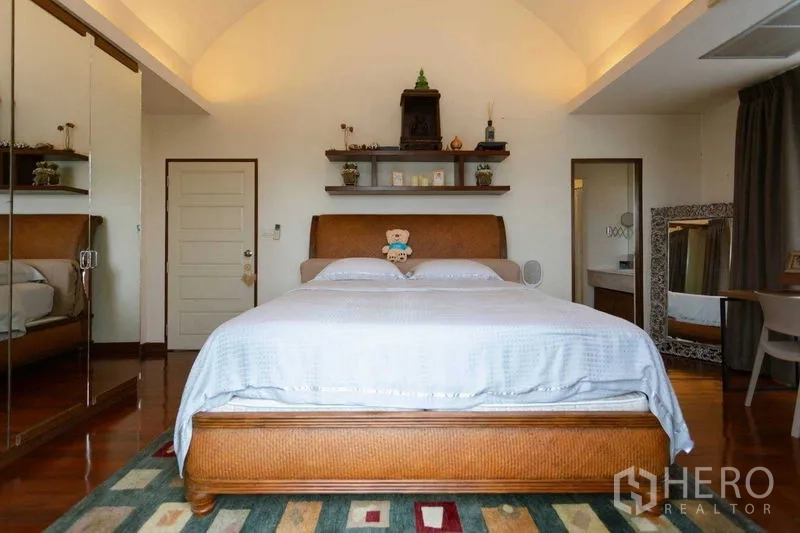 Home Office for sale in Watthana, Bangkok - Cozy second bedroom with mirrored wardrobe, shelving and wooden bed frame.
