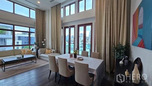 Condominium for rent in Pathum Wan, Bangkok - Double-height living and dining area with tall windows, balcony doors, and city views.