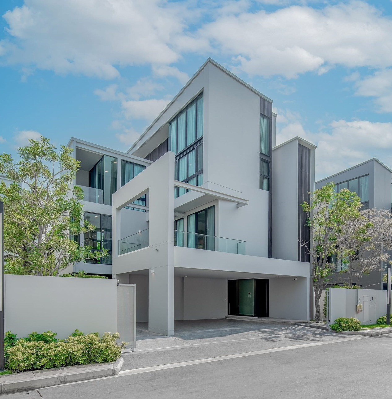 บ้าน ให้เช่าในSaphan Sung, Bangkok - ภาพภายนอกบ้านเดี่ยวสามชั้นสมัยใหม่ ระเบียงกระจก โรงจอดรถ และทางเข้าแต่งสวน