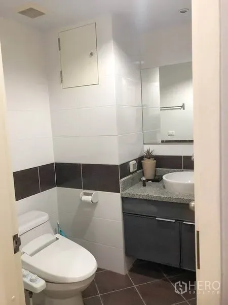 Condominium for rent or sale in Khlong Toei, Bangkok - Compact bathroom with toilet, vanity and wall mirror.
