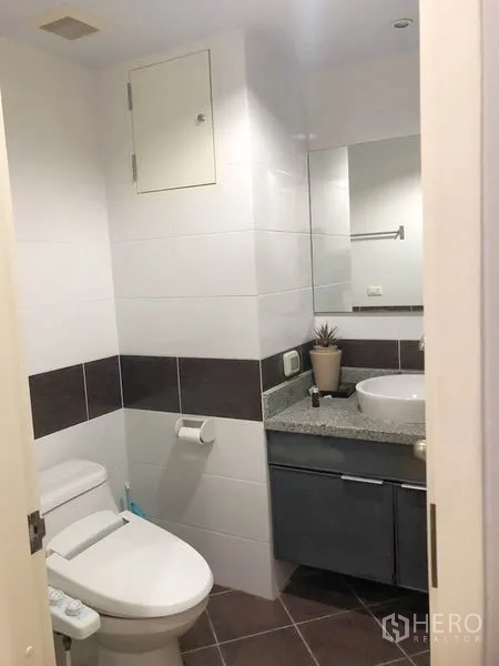 Condominium for rent or sale in Khlong Toei, Bangkok - Compact bathroom with toilet, vanity and wall mirror.