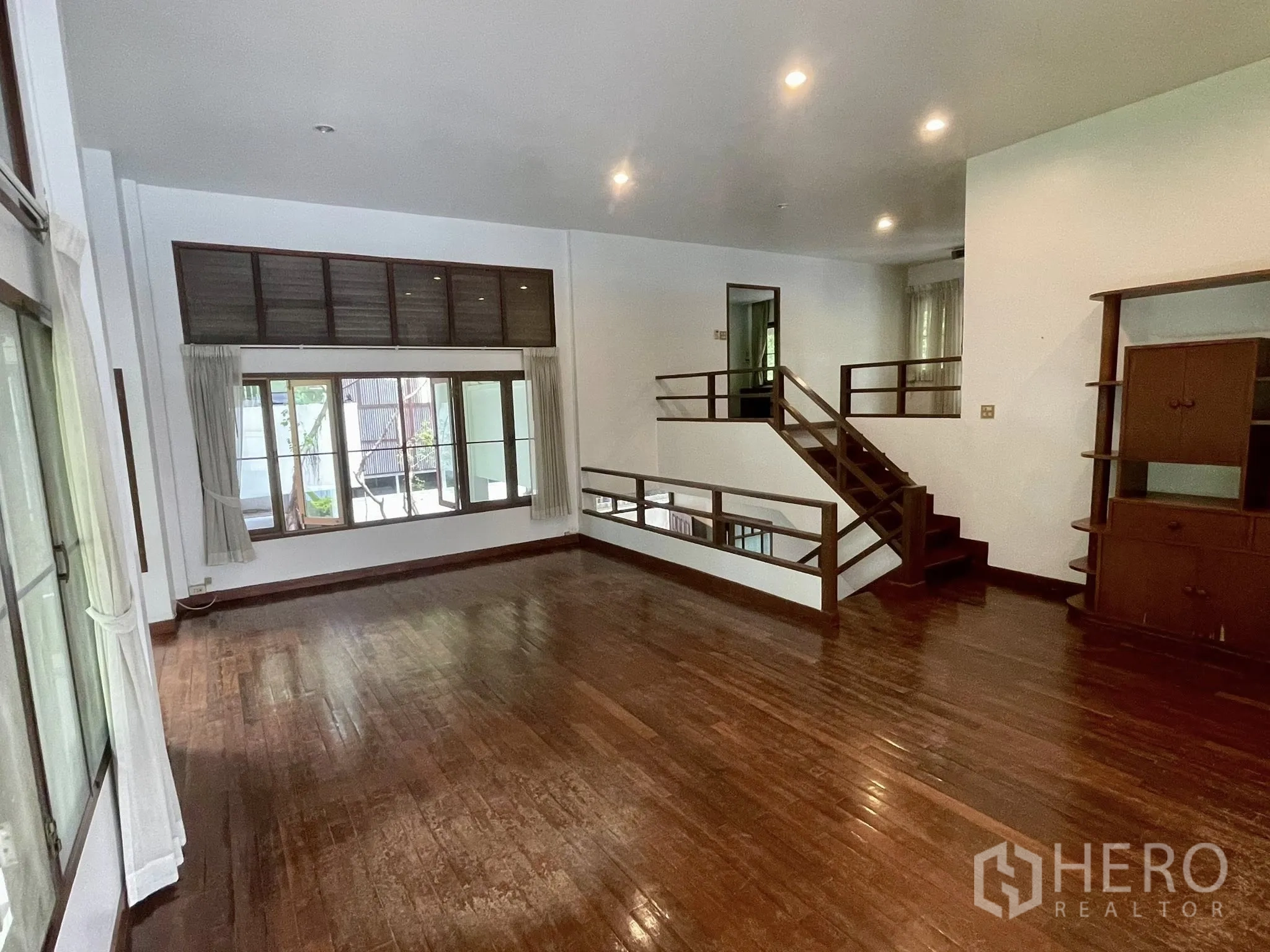 Detached House for rent in Pathum Wan, Bangkok - Spacious living area with steps to a raised level and wide windows.