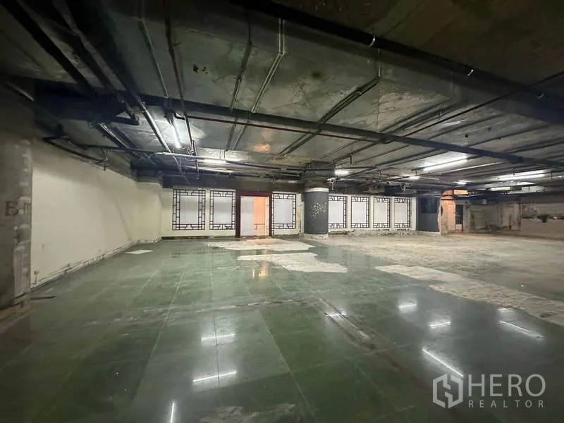 Retail Space for rent - Expansive retail interior with green tiles, blank display windows and exposed MEP on the ceiling.