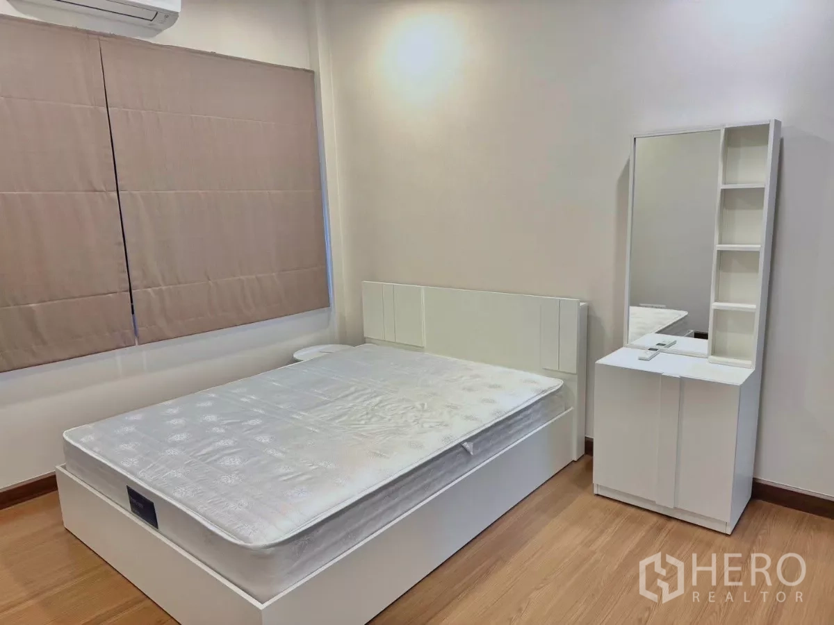 独立式住宅 出租在Bang Phli, Samut Prakan - 温馨次卧，白色床、梳妆台与木地板，配空调。