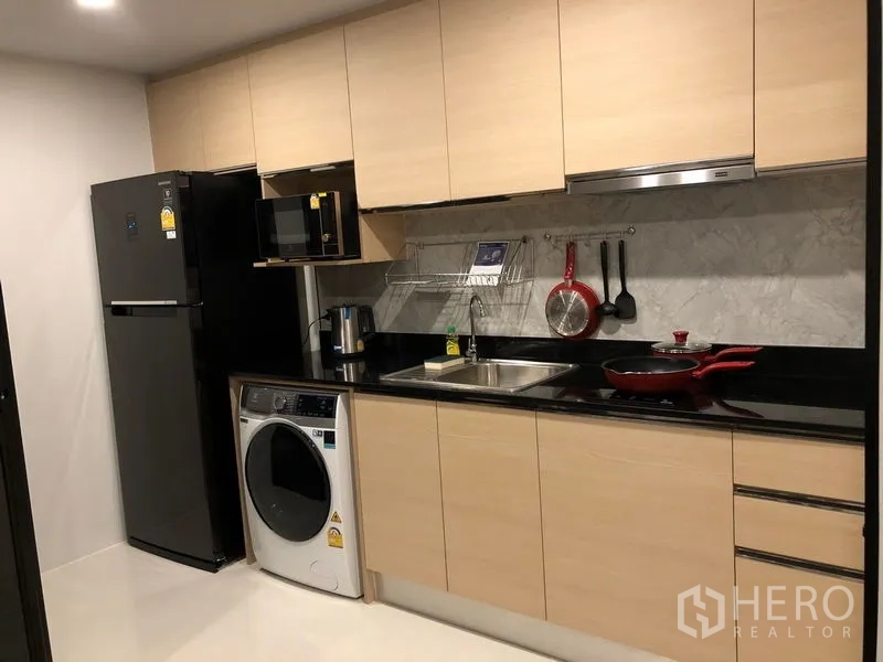 公寓 出租或出售在Yan Nawa, Bangkok - 一字型整体厨房，浅木柜体、黑色台面，配冰箱、微波炉和洗衣机。