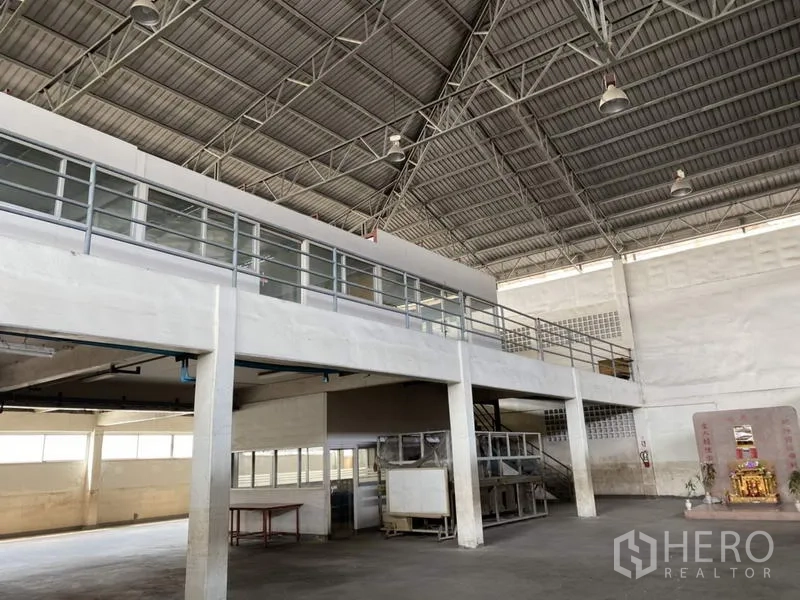 Factory for sale in Khlong Luang, Pathum Thani - Raised mezzanine office block with glass panels above the workshop floor.