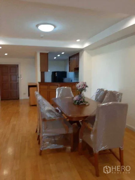 Apartment for rent in Watthana, Bangkok - Spacious dining zone facing the open kitchen, ceiling spotlights, and warm wood floors.