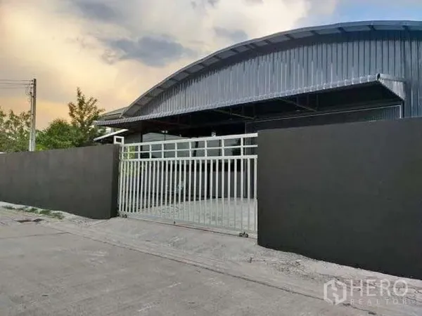Warehouse for rent in Khlong Sam Wa, Bangkok - Gated entry and front apron of a modern steel‑clad warehouse in Khlong Sam Wa, Bangkok.