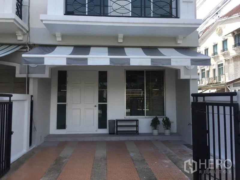 Townhouse for rent in Lat Phrao, Bangkok - Front porch with striped awning, white entrance door, large window and tiled parking bay.
