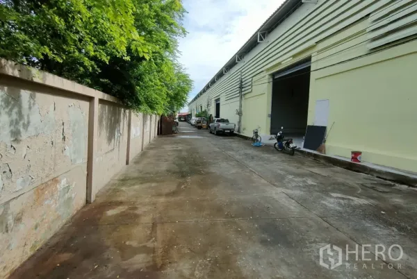 คลังสินค้า ให้เช่าในBang Sao Thong, Samut Prakan - ทางสัญจรข้างแถวโกดังยาว มีช่องขนถ่ายเปิดและต้นไม้ร่มรื่น