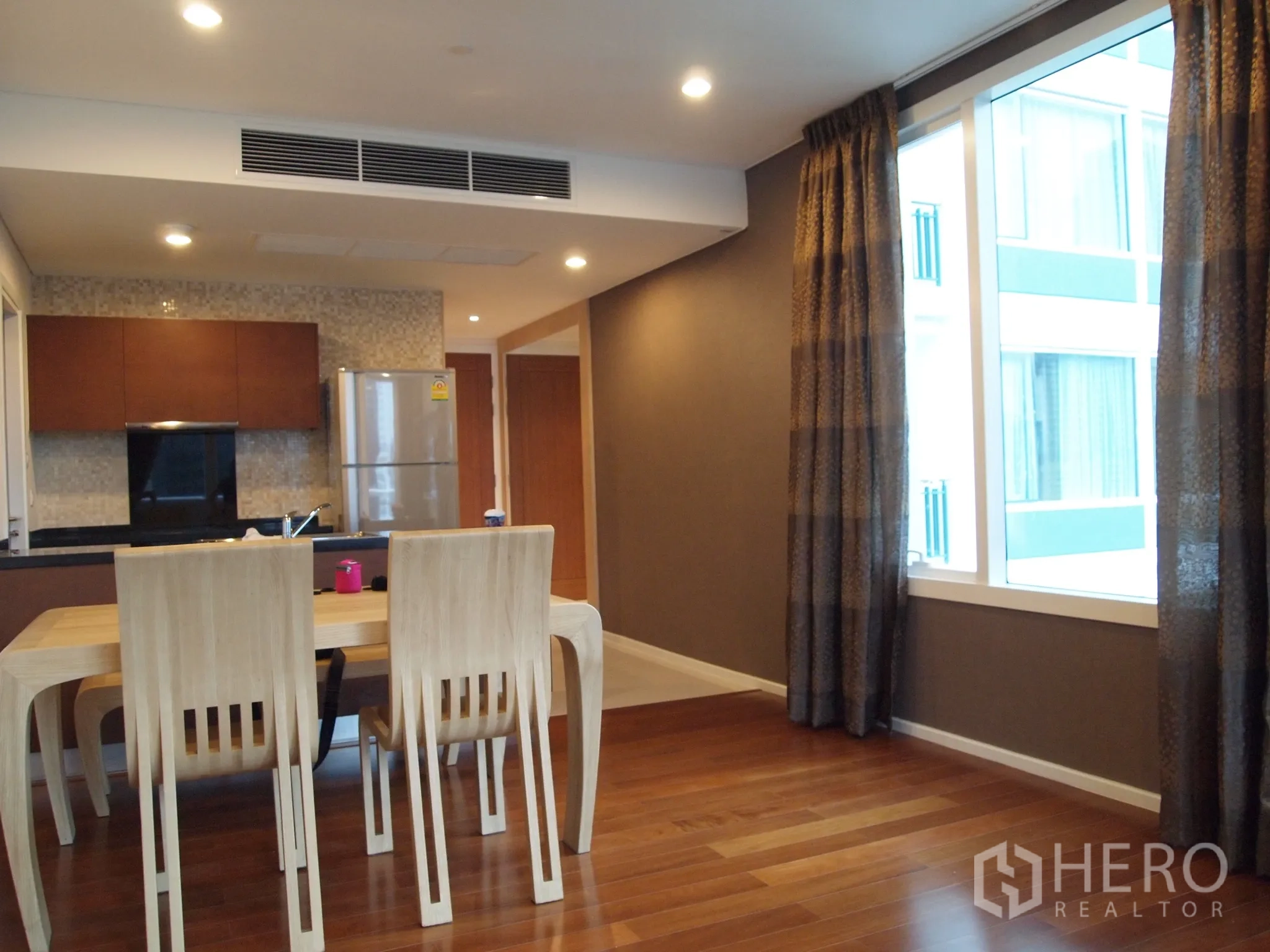 Condominium for rent or sale in Watthana, Bangkok - Bright dining space by large window next to kitchen with recessed lighting.