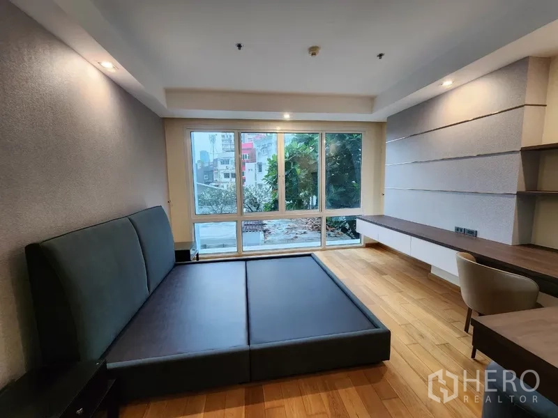 Condominium for rent in Khlong Toei, Bangkok - Bedroom with large windows, desk and upholstered platform bed.