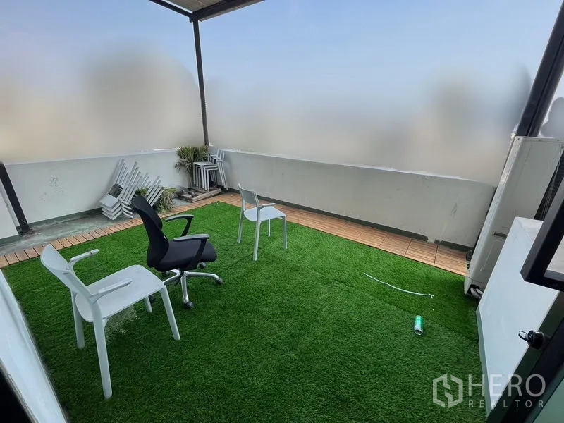 Office Space for rent in Khlong Toei, Bangkok - Private balcony terrace with artificial grass flooring and chairs, partially screened city views.