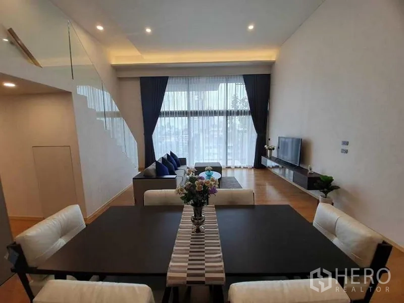 คอนโด ให้เช่าในWatthana, Bangkok - ห้องนั่งเล่นและรับประทานอาหารแบบเปิดโล่ง เพดานสูง ผ้าม่านหน้าต่างเต็มบาน พื้นไม้ และชั้นวางทีวี