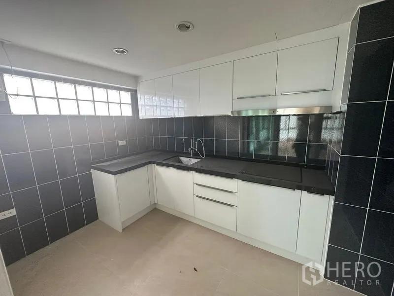 Home Office for rent in Bang Phli, Samut Prakan - L-shaped white built-in kitchen with dark countertops and tiled walls.