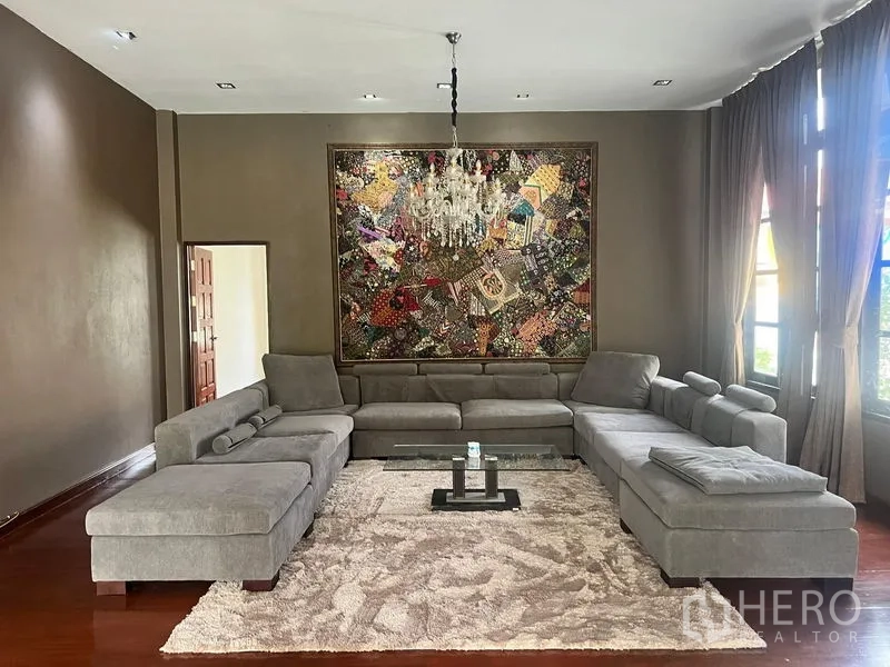 บ้าน ขายในPrawet, Bangkok - ห้องรับแขกกว้าง โซฟาเข้ามุมสีเทา โคมระย้า และงานศิลปะผนัง