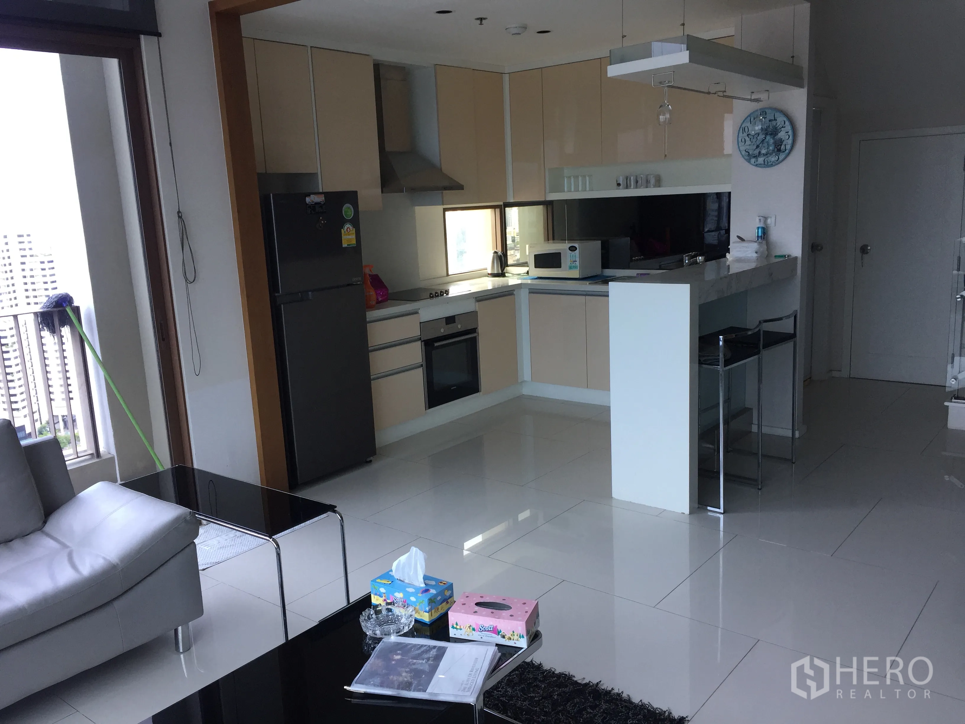 Condominium for rent or sale in Khlong Toei, Bangkok - Contemporary kitchen with built-in appliances, fridge and a breakfast bar beside the balcony.