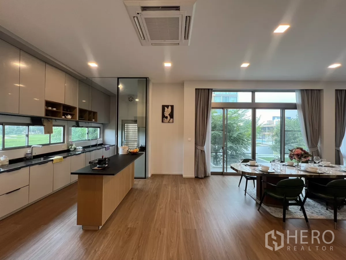 Detached House for rent in Saphan Sung, Bangkok - Open-plan kitchen with long island, full-height cabinetry and dining area beside tall windows.