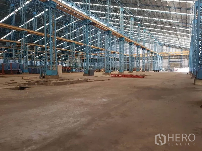 工厂 出租在Mueang Samut Sakhon, Samut Sakhon - 工厂内部高挑钢结构大厅，蓝色立柱、天窗与天车梁，空间开阔。