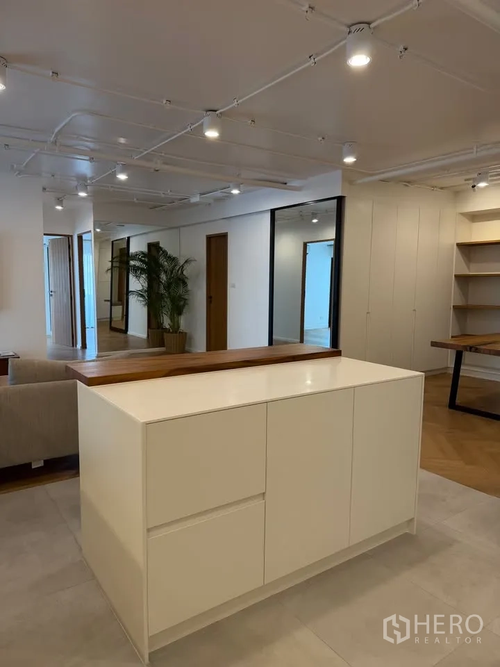公寓 for rent in Watthana, Bangkok - 开放式空间，白色中岛柜、轨道灯与绿植盆栽。