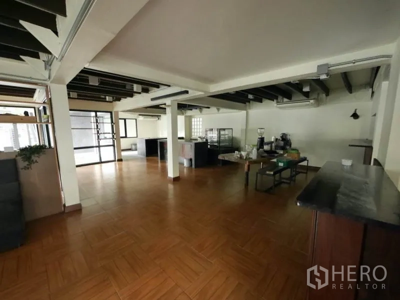 Retail Space for rent in Khlong Toei, Bangkok - Open-plan retail floor with wood-look tiles, exposed beams, glass entry and service counters.
