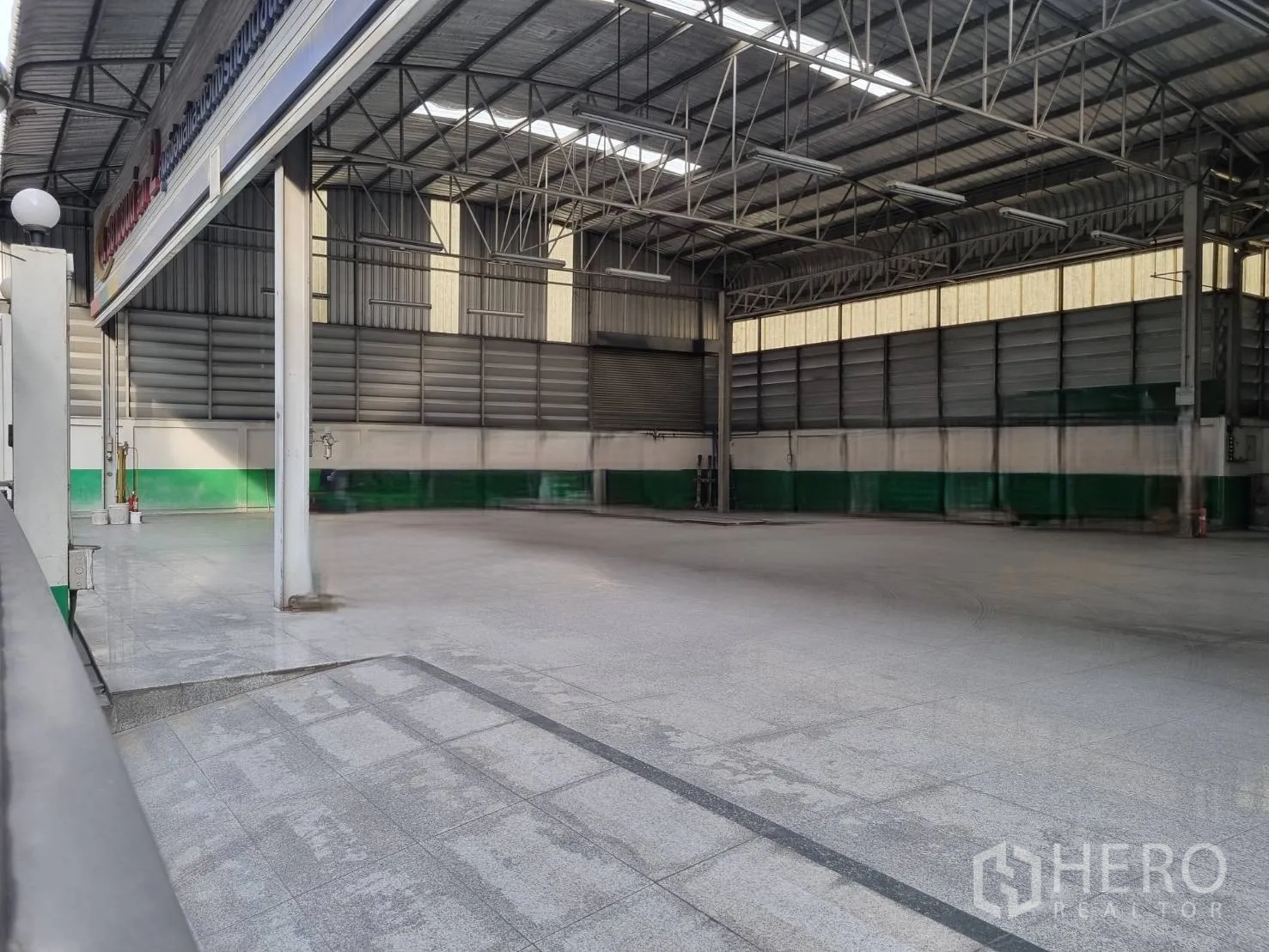 Warehouse for sale in Yan Nawa, Bangkok - Wide open warehouse floor with high roof, columns, and shuttered bays for loading.