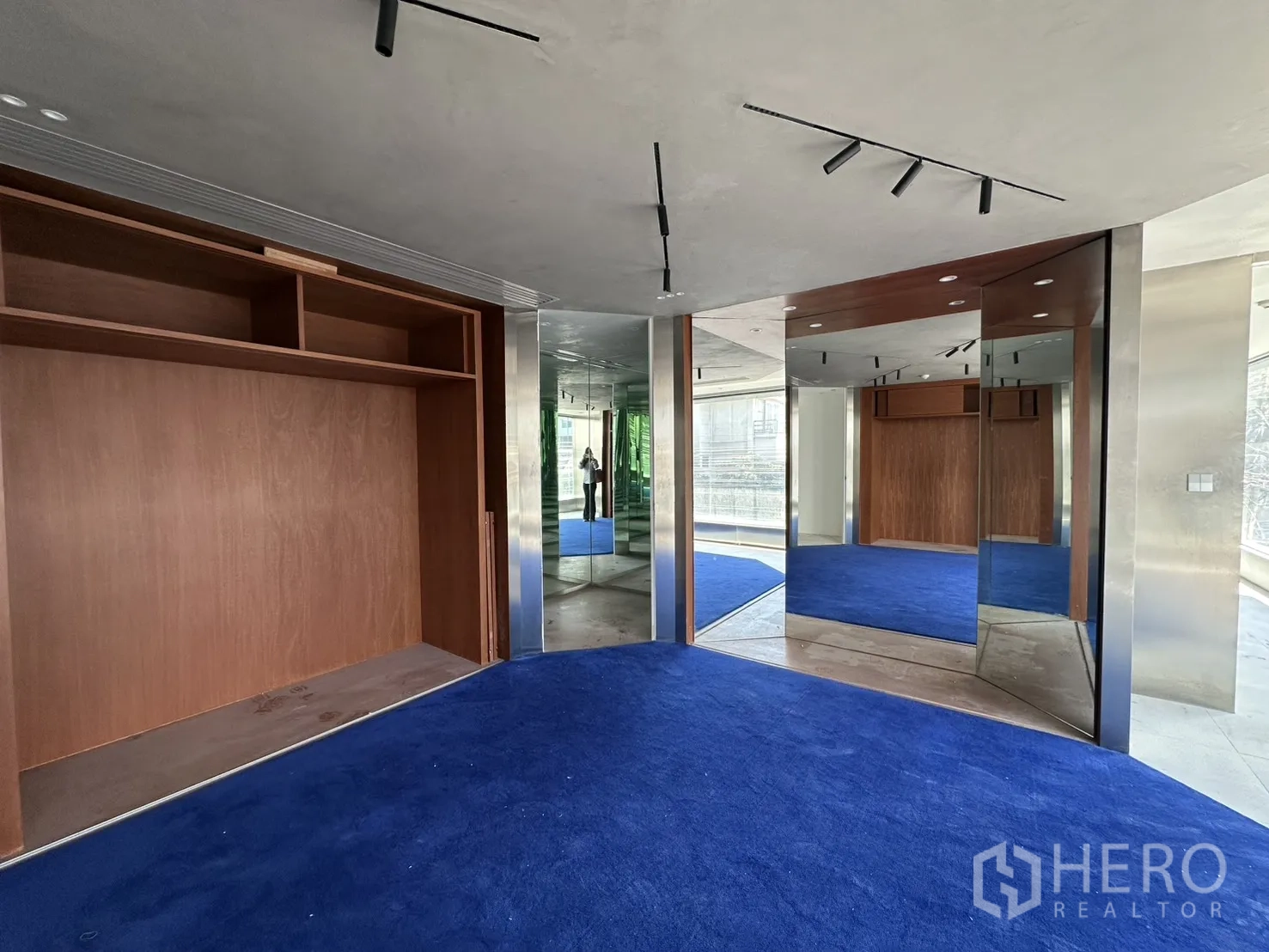 พื้นที่ขายของ for rent in Watthana, Bangkok - มุมโชว์รูมพร้อมกระจกเงา ตู้บิลท์อินไม้ และพรมสีน้ำเงิน.
