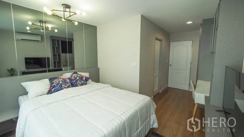 Condominium for rent in Khlong San, Bangkok - Second bedroom with bed, mirrored wall, study desk, and wardrobe storage.