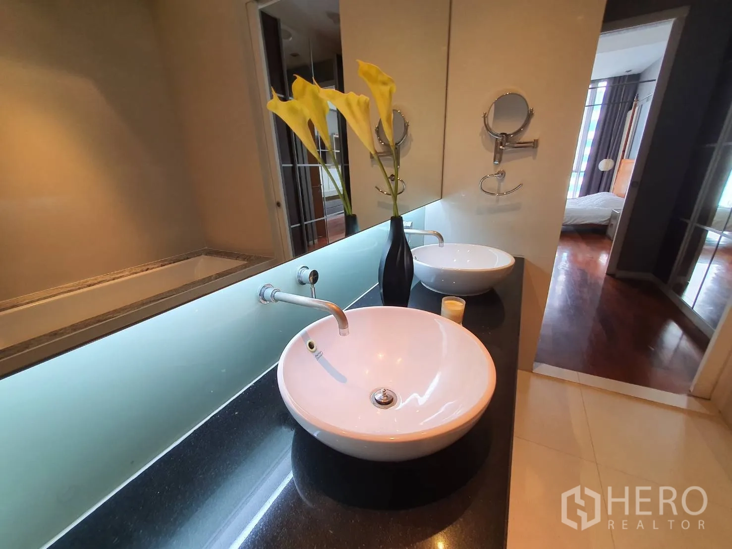 Condominium for rent in Khlong Toei, Bangkok - Primary bathroom with twin vessel sinks, soaking tub and a long backlit mirror.