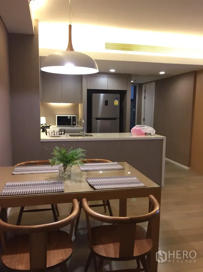 公寓 出租在Watthana, Bangkok - 开放式用餐区，木质餐桌与吊灯，连接现代厨房中岛。
