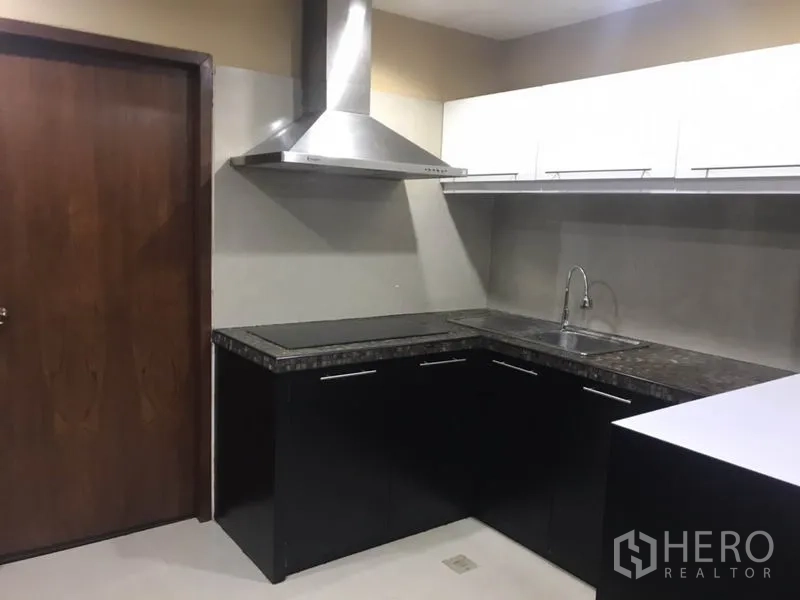 Condominium for rent in Watthana, Bangkok - Modern L-shaped kitchen with stone countertops, sink and range hood.