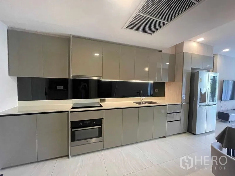 公寓 出租或出售在Watthana, Bangkok - 开放式现代厨房，亮面橱柜、嵌入式烤箱与不锈钢冰箱。