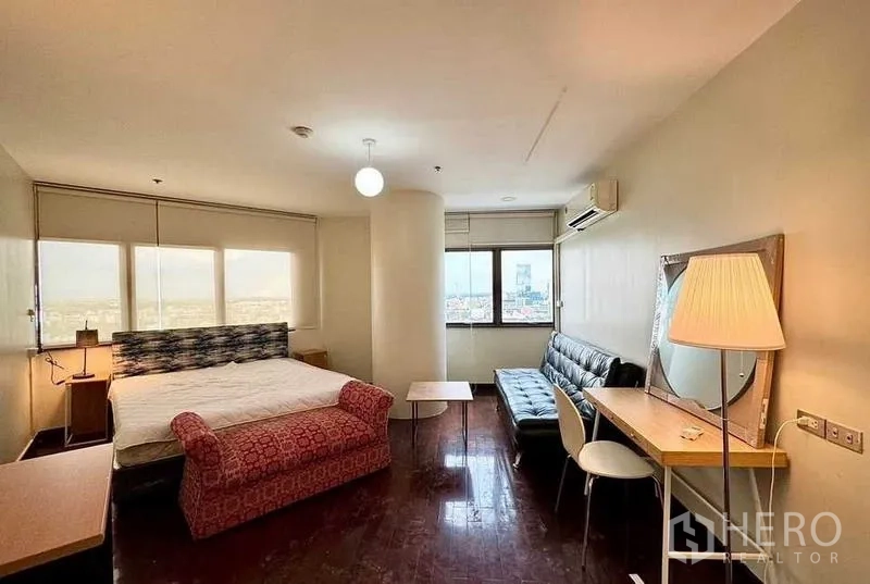 公寓 出租或出售 - 主卧配大窗、沙发休闲区与带台灯的书桌。