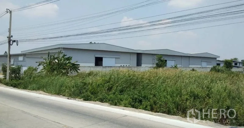 Warehouse for rent in Pathum Thani - Low-rise warehouse buildings with roadside frontage and surrounding greenery.