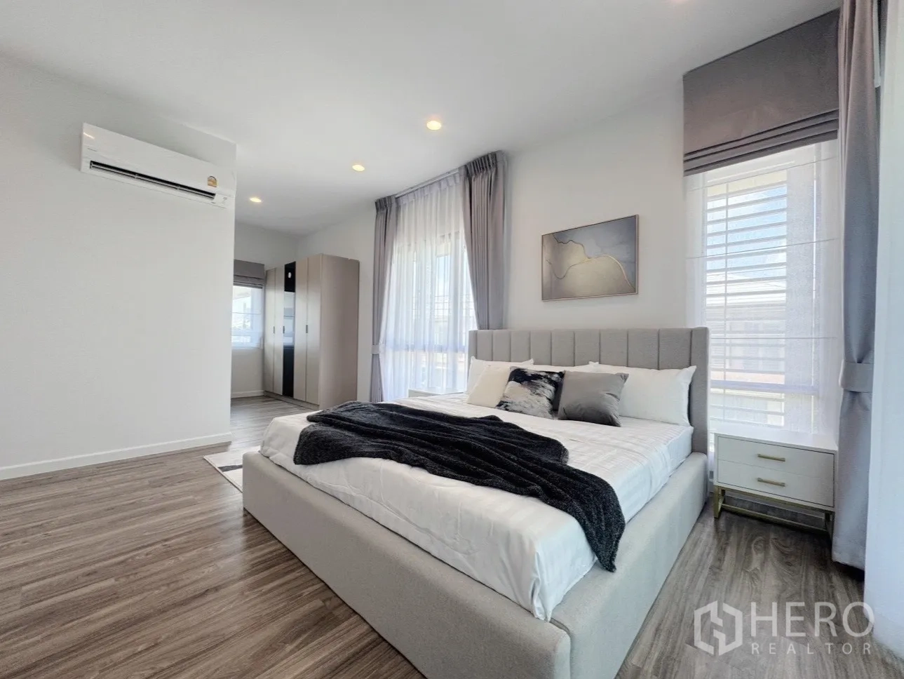 Detached House for rent or sale in Bang Kapi, Bangkok - Master bedroom angle showing bed, wardrobes and warm wood floors.