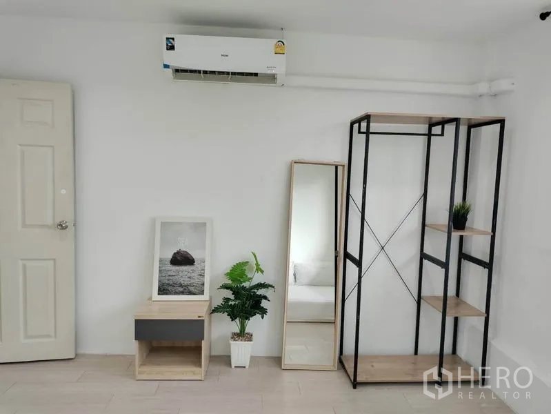 Home Office for rent - Close-up of shelving unit, tall mirror, air conditioner and a small side table with plant.