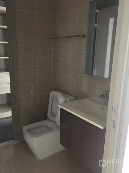 Condominium for sale in Din Daeng, Bangkok - Modern tiled bathroom with toilet, floating vanity and mirror cabinet in a Bangkok condominium.