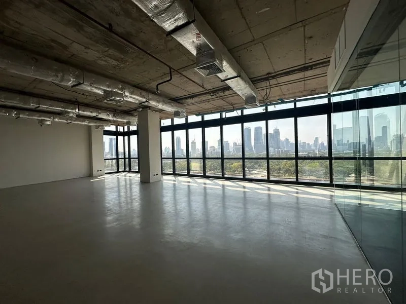 办公空间 出租在Watthana, Bangkok - 开放工作区，通高玻璃、工业风天花与玻璃隔间，享受城市与公园景观。