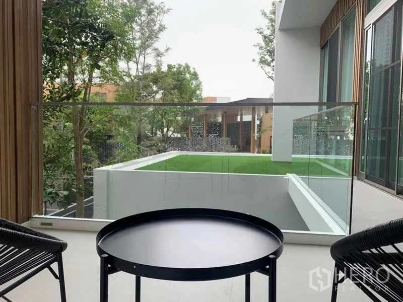独立式住宅 出租在Saphan Sung, Bangkok - 玻璃护栏阳台，户外座椅，可赏绿意与现代建筑立面。