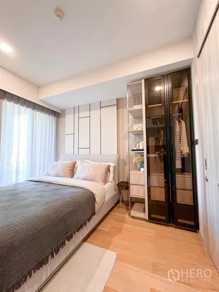 Condominium for rent in Watthana, Bangkok - Second bedroom with bed, glass-door wardrobe, and sheer curtains.