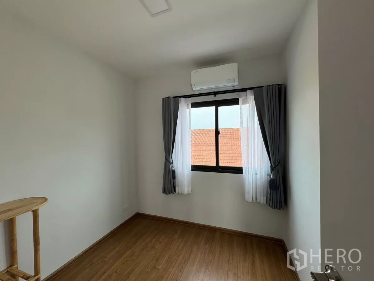 Townhouse for rent in Bang Phli, Samut Prakan - Empty air-conditioned room with wood floors and curtained window.