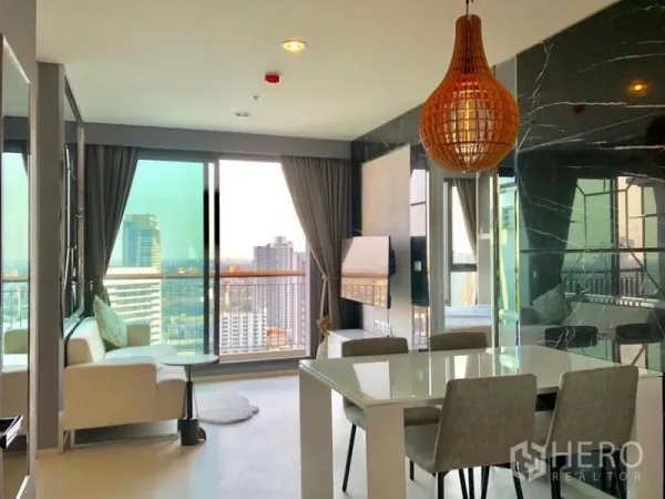 Condominium for rent in Khlong Toei, Bangkok - Bright living-dining space with large glass doors to the balcony and skyline views.