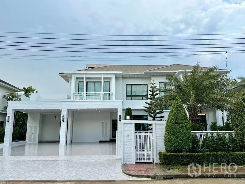 独立式住宅 出租在Lat Krabang, Bangkok - 现代白色两层独栋别墅，带大门、宽敞车棚与修剪整齐的棕榈景观