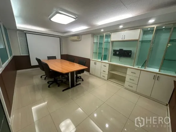 Office Space for sale - Conference room with wooden table, built-in cabinets, projector screen and recessed lights.
