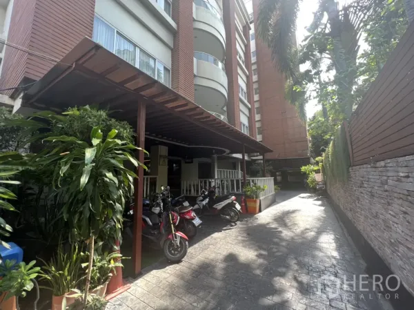 零售空间 出租在Khlong Toei, Bangkok - 建筑外立面，带遮棚的门廊、盆栽与机车停放区。