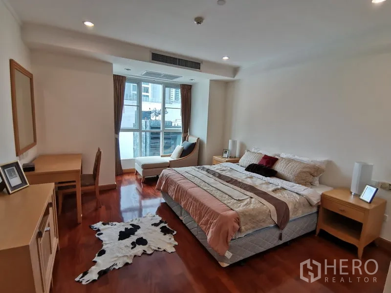 Condominium for rent in Khlong Toei, Bangkok - Master bedroom with king bed, bay window seating, work desk, and warm wood floors.