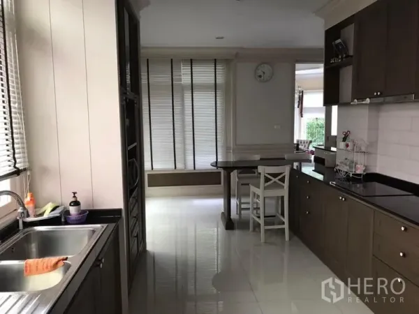 独立式住宅 出租在Bang Khen, Bangkok - 开放式厨房，黑色石材台面、水槽与带百叶窗的窗户。