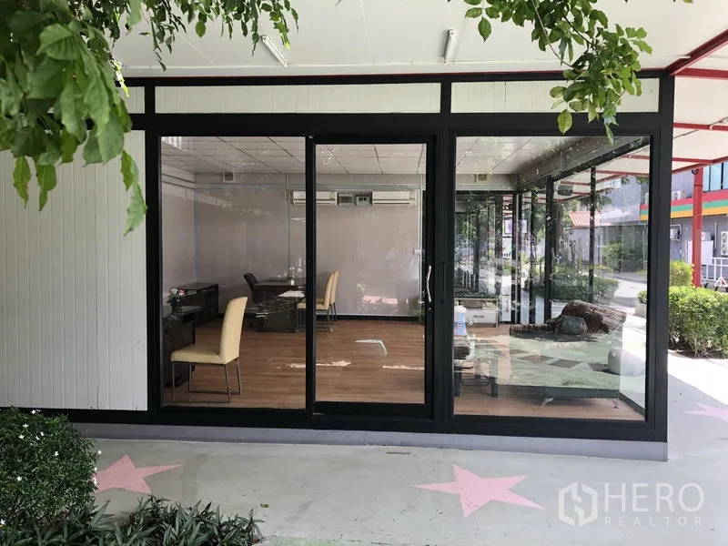 Office Space for rent in Wang Thonglang, Bangkok - Ground-floor office with full-height glass frontage, wood-look flooring, and desks in Wang Thonglang, Bangkok.