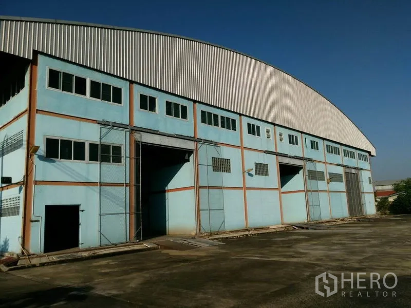 Factory for sale in Lat Lum Kaeo, Pathum Thani - Curved metal-roof factory facade with clerestory windows and tall openings for logistics access.