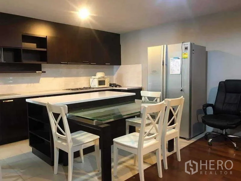 Condominium for sale in Yan Nawa, Bangkok - Kitchen angle highlighting stainless fridge, dark cabinets and island seating.